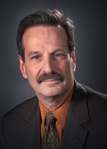 Richard Schwarz wearing a brown tie and jacket with an orange shirt